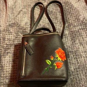 Black shoulder backpack with a rose in the front